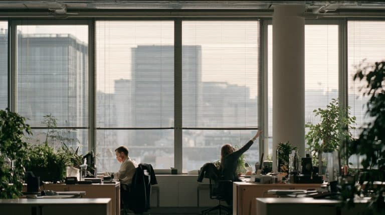 Bureau paysager lumineux, occupants réglant les stores près des fenêtres